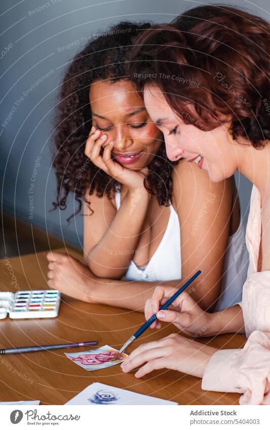 Lesbische Paar Färbung Bild auf Papier zu Hause lesbisch zeichnen Zusammensein positiv Glück Pinselblume Lächeln Frauen Freundin Tisch heimwärts multiethnisch