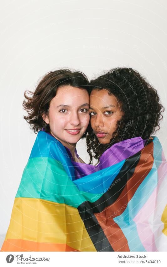 Seitenansicht verschiedener junger Freunde mit LGBT-Flagge lesbisch Paar Fahne lgbt Partnerschaft Liebe Umarmung Lächeln Umarmen Frau vielfältig multiethnisch