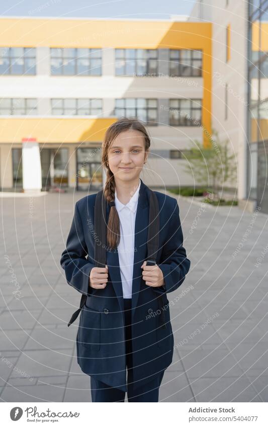 Selbstbewusstes junges Schulmädchen im Teenageralter mit Rucksack Uniform Schüler Jugendlicher Lächeln Schule Pupille Gebäude Mädchen heiter Glück Bildung