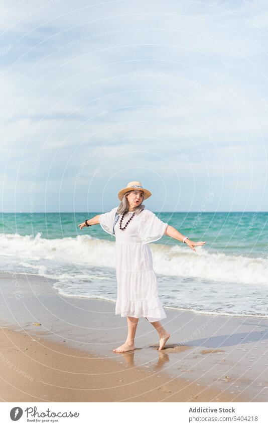 Positive Frau, die am Sandstrand spazieren geht Glück Strand Freiheit genießen Urlaub Sommer MEER Natur älter Senior Rentnerin gealtert reif Ufer winken Wasser