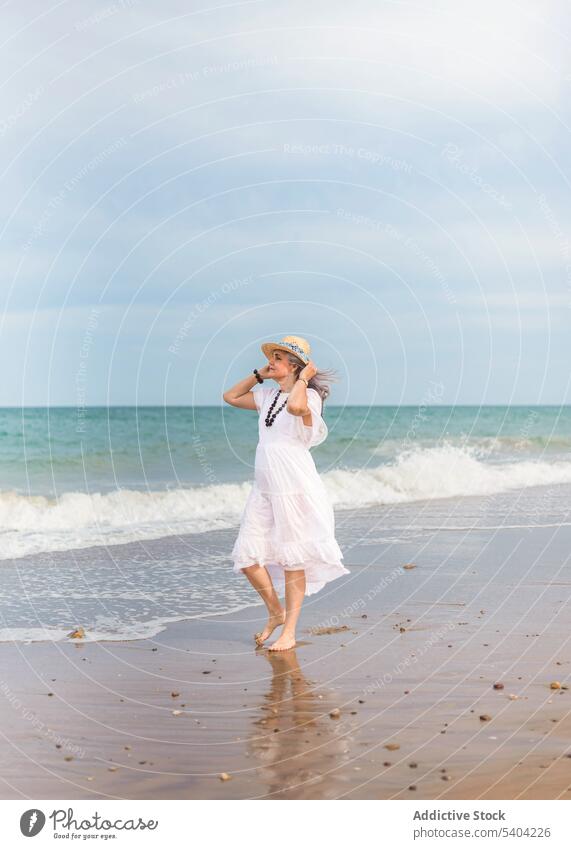 Glückliche Frau, die am Sandstrand spazieren geht Strand Freiheit genießen Urlaub Sommer MEER Natur älter Senior Rentnerin gealtert Ufer Himmel winken Wasser
