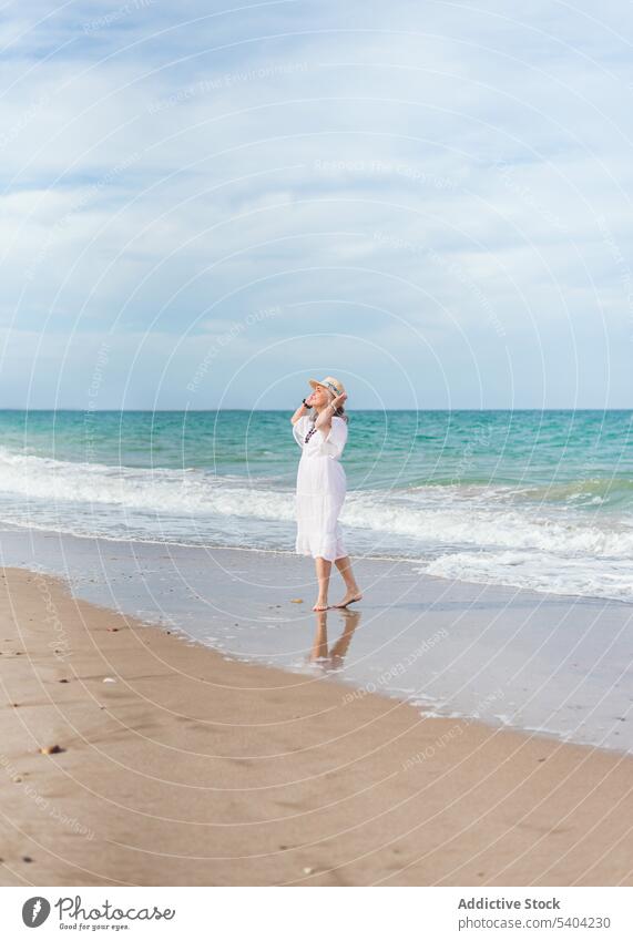 Glückliche Frau, die am Sandstrand spazieren geht Strand Freiheit genießen Urlaub Sommer MEER Natur älter Senior Rentnerin gealtert Ufer winken Wasser