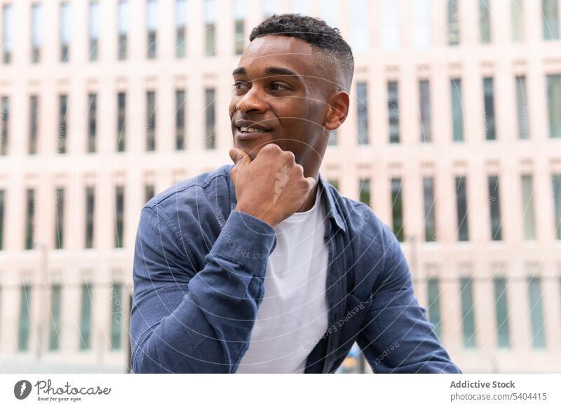Fröhlicher schwarzer Mann ruht sich im Stadtzentrum aus sich[Akk] entspannen ruhen Großstadt Straße freundlich Lächeln Porträt männlich Afroamerikaner Kälte