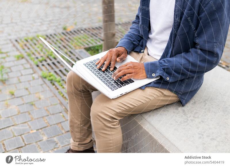 Anonyme Ernte schwarzer Mann mit Laptop auf der Straße freiberuflich Computer abgelegen Arbeit Projekt Browsen Internet männlich Afroamerikaner Unternehmer
