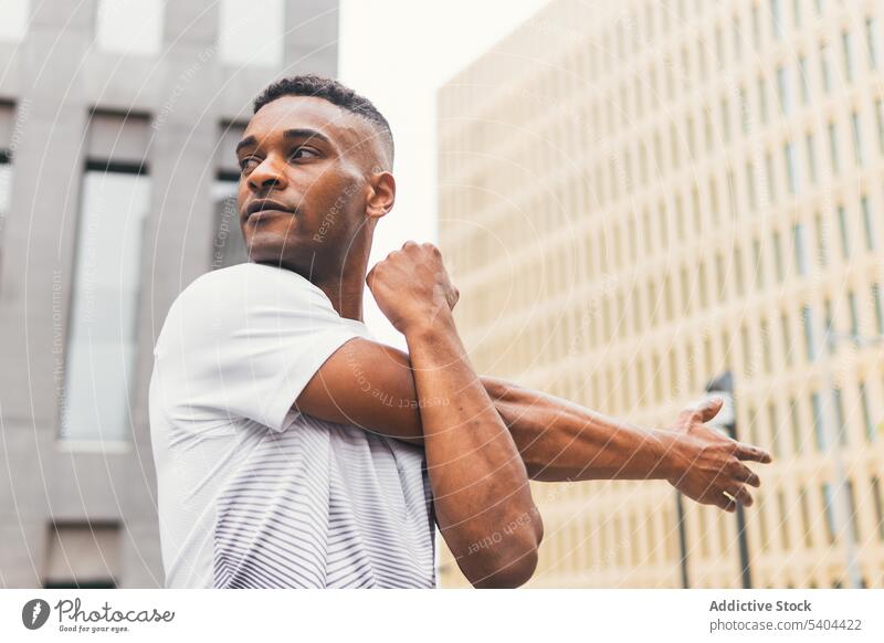 Schwarzer Mann streckt Arme auf der Straße aus Athlet Dehnung Aufwärmen Übung Training Sportbekleidung Großstadt Wolkenkratzer männlich schwarz Afroamerikaner