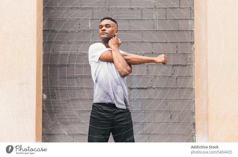 Schwarzer Mann streckt Arme auf der Straße aus Athlet Dehnung Aufwärmen Übung Training Sportbekleidung Großstadt männlich schwarz Afroamerikaner Fitness