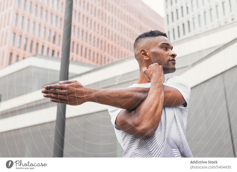 Schwarzer Mann streckt Arm auf Straße Athlet Dehnung Aufwärmen Übung Training Sportbekleidung Großstadt männlich schwarz Afroamerikaner Fitness physisch