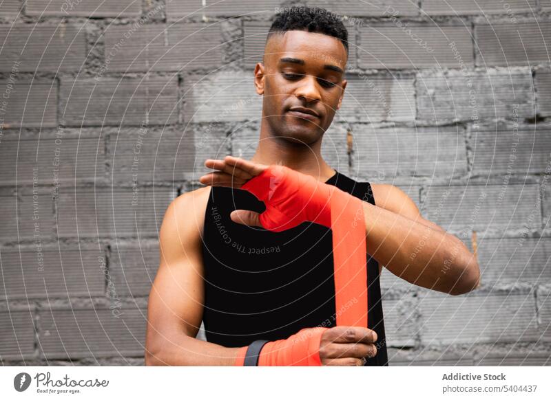 Schwarzer Sportler wickelt Hände zum Boxen Athlet Boxsport umhüllen elastisch bandagieren Training Fitnessstudio vorbereiten Sportbekleidung männlich schwarz
