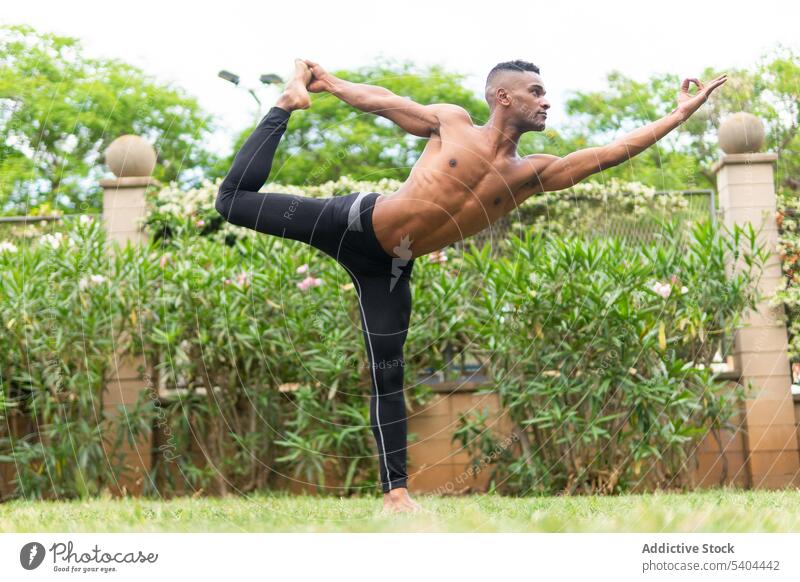 Schwarzer ruhiger Mann macht Yoga in Tänzerpose Athlet Natarajasana Pose Dehnung Bein gyan Mudra tropisch männlich schwarz Afroamerikaner Asana Gleichgewicht