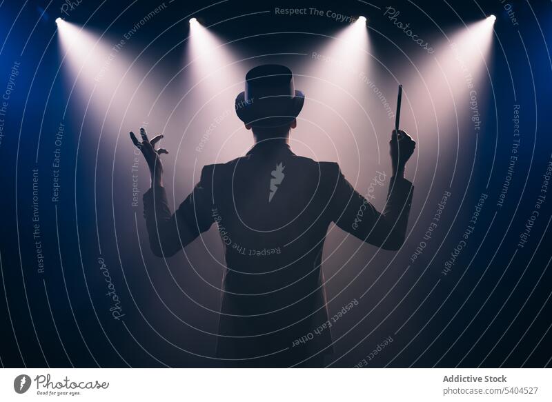 Mann mit Zauberstab auf der Bühne im Scheinwerferlicht Illusionist Zauberei u. Magie kleben ausführen Präsentation Top Hut Anzug männlich Zauberer Abrakadabra