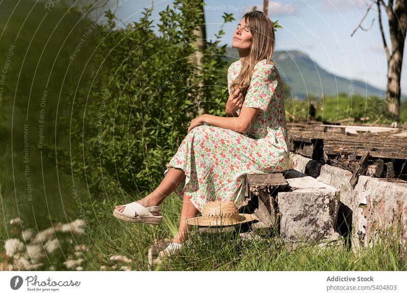Entspannende Frau auf der Veranda in der Landschaft sitzend Sonnenlicht genießen Sommer Freizeit Windstille Natur sorgenfrei Augen geschlossen Harmonie ruhig