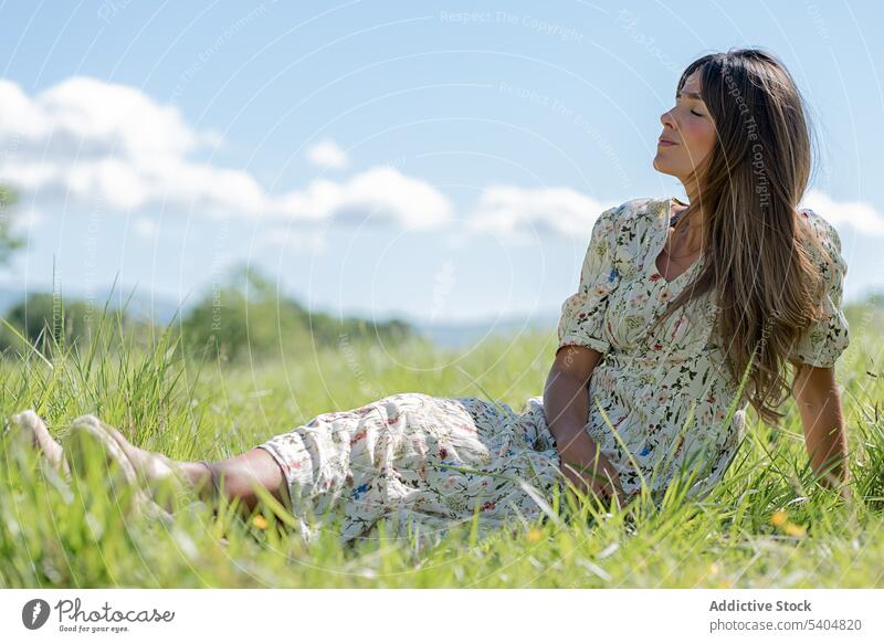 Verträumte Frau, die im Tal im Gras liegt genießen Sommer ruhen Landschaft Rasen Natur Harmonie sich[Akk] entspannen grün Gelassenheit Freiheit Wiese Kleid