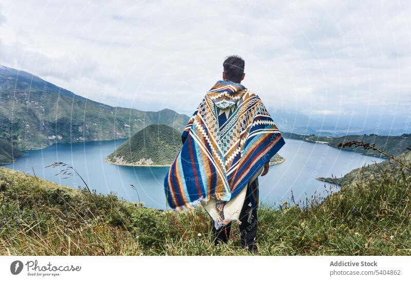 Unbekannter Mann in warmer Kleidung steht auf einer Wiese und genießt den Blick auf den See Reisender bewundern Berge u. Gebirge Hochland Natur Landschaft