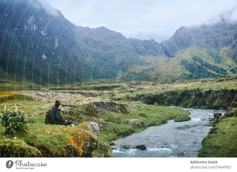 Reisende Frau sitzt auf einem Stein am Fluss Berge u. Gebirge bewundern Vulkan Tal Reisender Natur Hochland Tourist Rucksack spektakulär Altar Ecuador malerisch