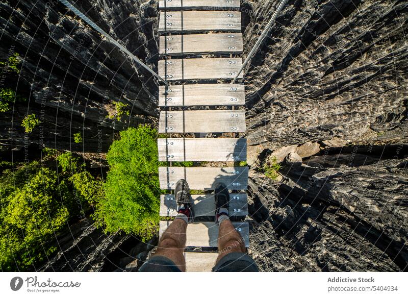 Unbekannter Tourist auf einer Holzbrücke stehend Mann Reisender Brücke erkunden Suspension Abenteuer Seil hölzern Klippe Tal männlich Formation Park Stein Natur