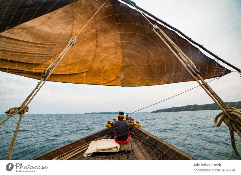 Anonymer Mann sitzt auf einem Boot im plätschernden Meer Fischer Segelboot Fischen Schwimmer Rippeln wellig Meerwasser Windstille endlos MEER Verkehr