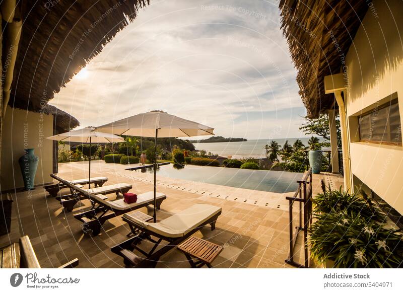 Schwimmbad in einem tropischen Resort an der Meeresküste Pool Hotel Sonnenbank Urlaub üppig (Wuchs) Sommer räkeln Grün exotisch Erholung Feiertag Regenschirm