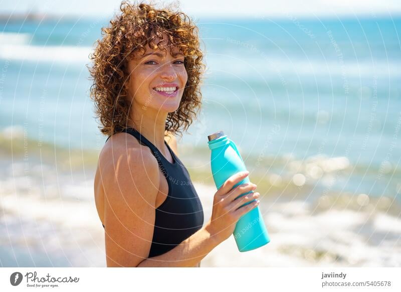 Glückliche Sportlerin trinkt Wasser am Strand Athlet trinken Flasche Durst Training MEER Pause Sommer Frau ernst Gesundheit Fitness Wellness passen Erfrischung