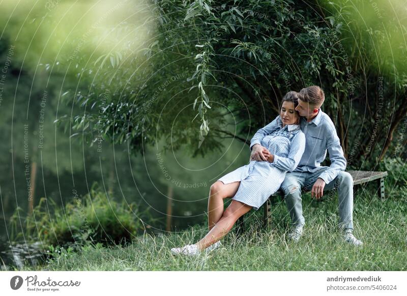 Junges Paar umarmt sich und sitzt in der Nähe des Sees an einem sonnigen Tag. Mann und Frau im Sommerurlaub. Konzept der schönen Familie. selektiver Fokus jung