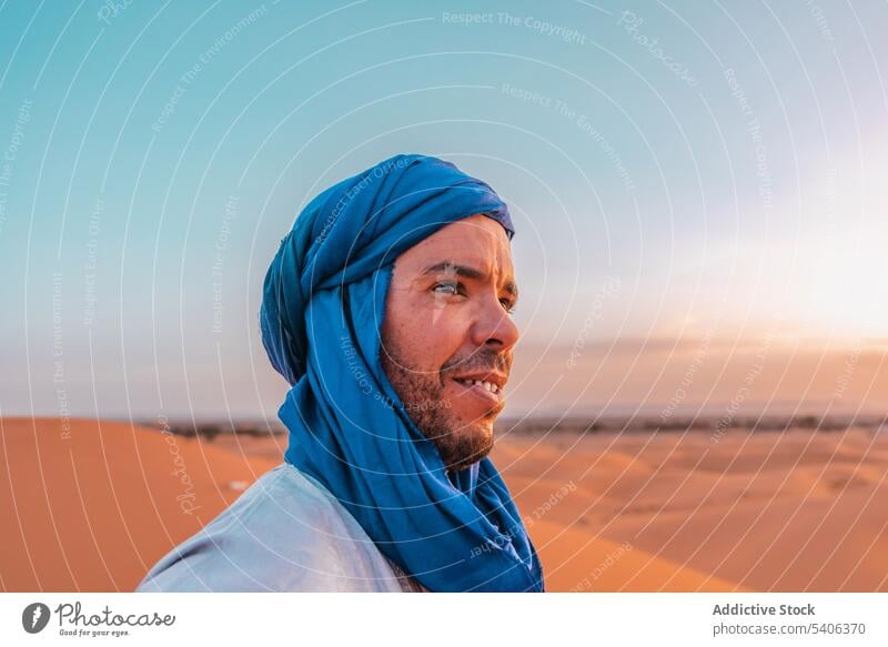 Lächelnder ethnischer Mann mit blauem Turban in der Wüste stehend Berber Tradition wüst Glück nachdenken tuareg Sand Natur Merzouga Marokko muslimisch