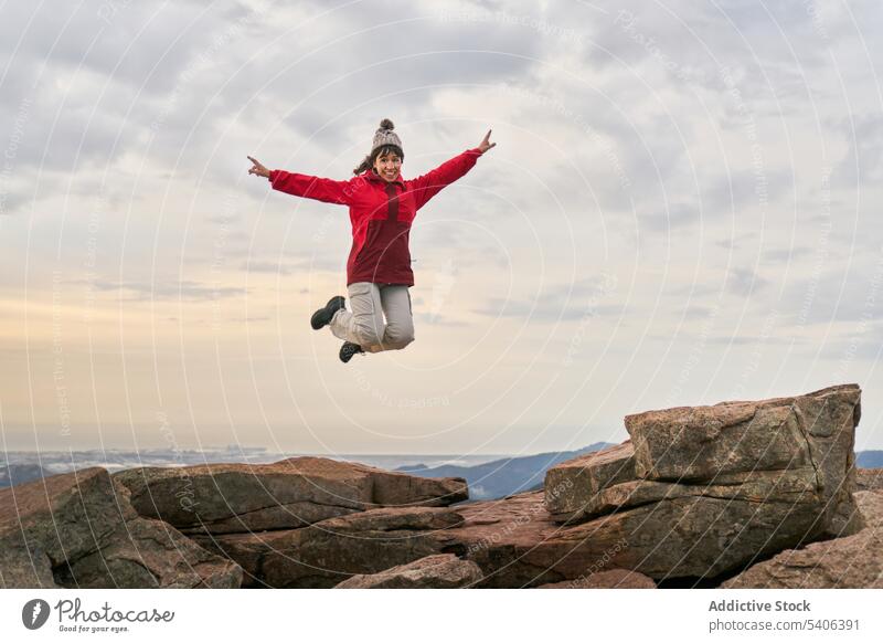 Unbekümmerte Frau springt bei Sonnenuntergang von einer Bergklippe aufgeregt springen Reisender Trekking Erfolg Berge u. Gebirge felsig Klippe el garbi Glück