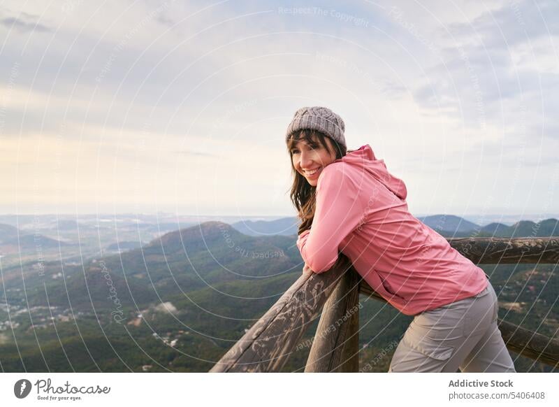 Fröhliche Frau lehnt an einem Zaun in den Bergen Tourist Reisender Berge u. Gebirge Reling bewundern Hochland beobachten Urlaub Aussichtspunkt Ausflug reisen
