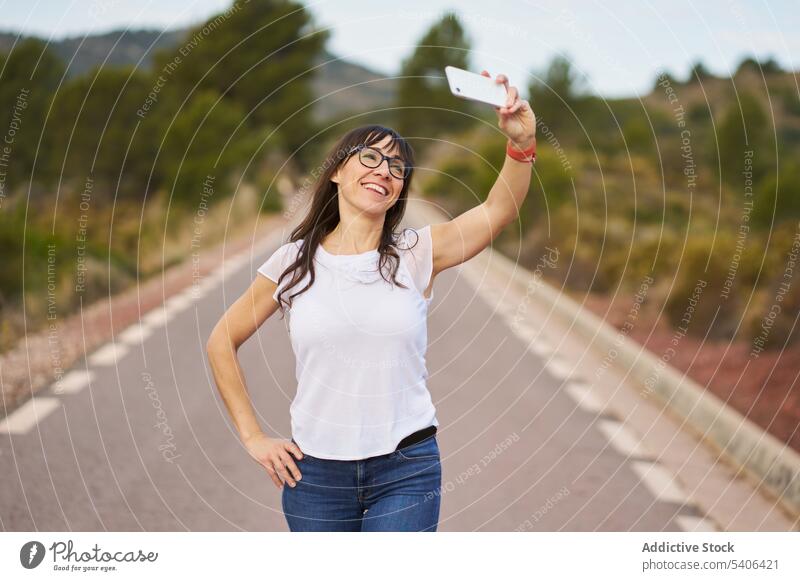 Fröhliche Frau mit stehendem und Selfie auf der Straße Reisender Smartphone Tourist fotografieren Landschaft Urlaub Erwachsener Apparatur Gerät Mobile Telefon