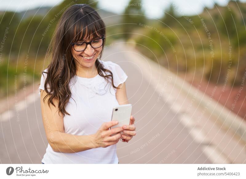 Glückliche Frau, die ihr Smartphone durchsucht und auf der Straße steht benutzend Textnachricht Tourist prüfen Internet online Urlaub Erwachsener Mobile Telefon