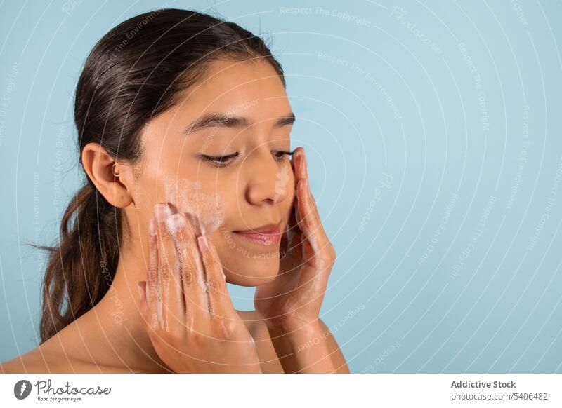 Ethnische Frau, die während einer Schönheitsoperation Seife auf die Wangen aufträgt schäumen Kosmetik Produkt Hautpflege bewerben Routine Kosmetologie Lächeln