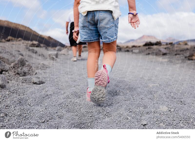 Unbekannter Mann und Kind gehen bei Tageslicht auf trockenem Boden folgen Spaziergang Turnschuh trocknen Gelände Landschaft männlich Sommer Zusammensein