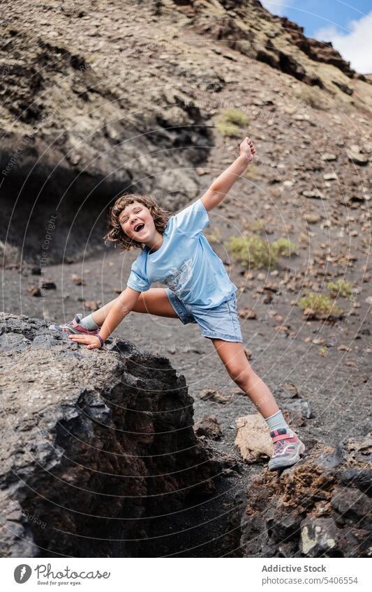 Fröhliches Kind genießt die Freiheit in felsigem Gelände in der Nähe des Berges Lächeln Stein Glück heiter positiv genießen Dehnung sich auf die Hand lehnen