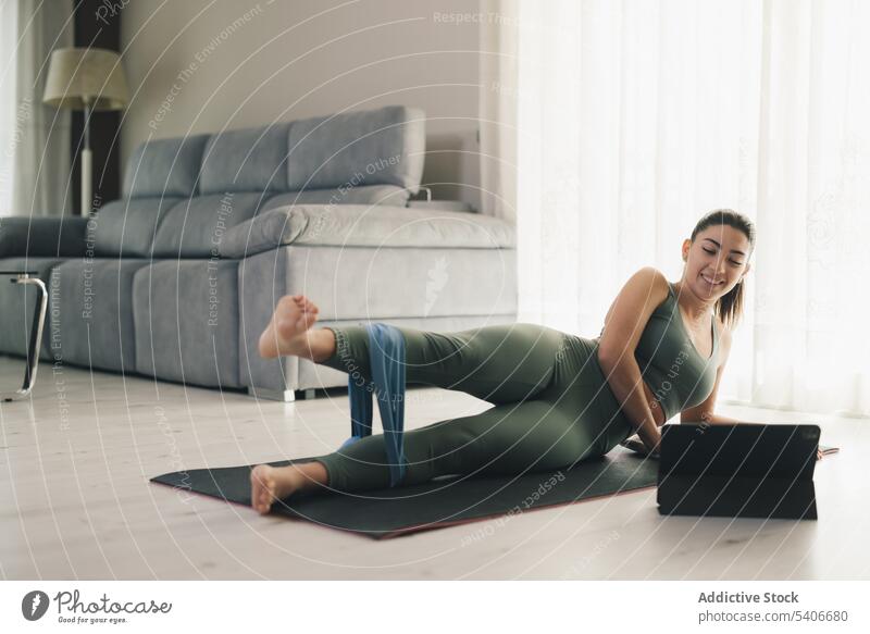 Lächelnde junge Frau beobachtet Tablet und macht Yoga in Pose Dehnung Übung beweglich Training Unterlage Schiffsplanken Band Tablette Barfuß Wellness Sportlerin
