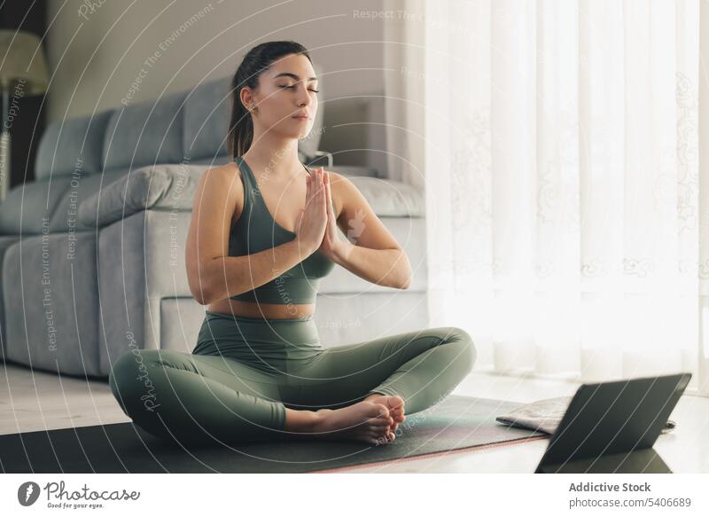 Schöne junge Frau macht Online-Yoga zu Hause Sportlerin Lotus-Pose meditieren padmasana Asana heimwärts Achtsamkeit Windstille sich[Akk] entspannen üben