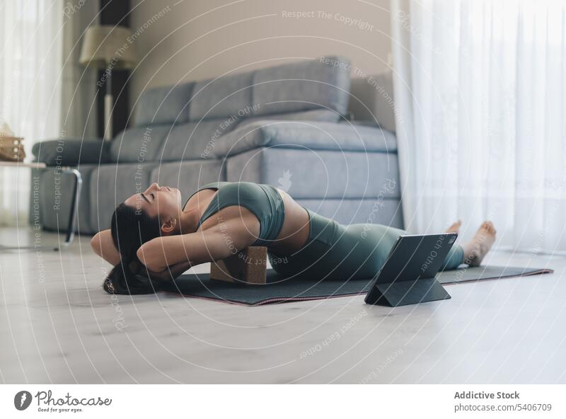 Sportlerin beim Üben der Fisch-Pose mit einem Yoga-Block zu Hause matsyasana Klotz Tablette online Asana Dehnung Gleichgewicht Frau beweglich üben Tutorial jung
