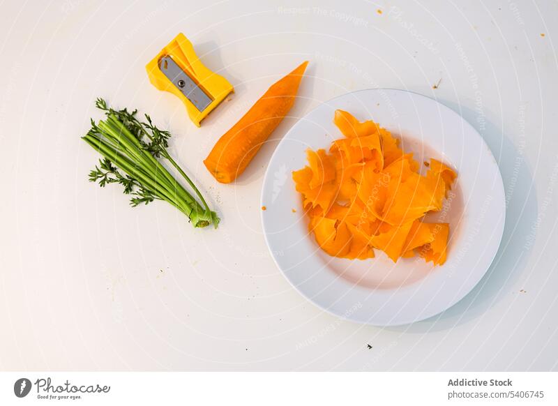 Teller mit frischer, geschälter Karotte und Anspitzer auf dem Tisch Möhre Gemüse Scheibe Vorbau geschnitten Vegetarier Lebensmittel Stengel Diät organisch grün