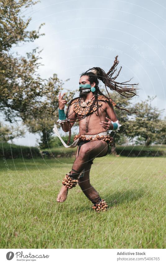 Fröhlicher Mann in Tracht und mit fliegenden Haaren tanzt im Freien Tanzen Park Mundschutz ausführen Spaß haben Tradition Accessoire feiern positiv Freude