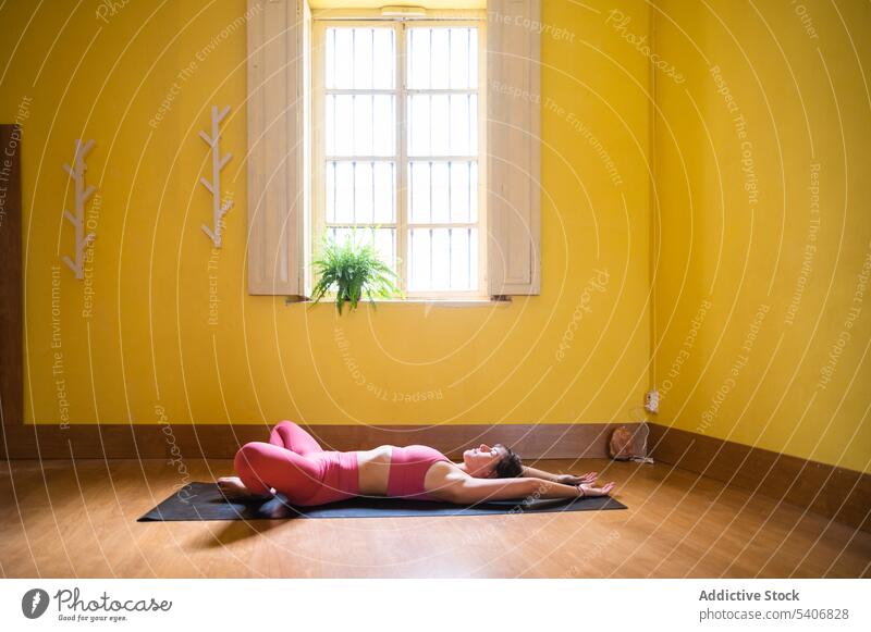 Flexible Frau auf der Matte liegend und in der Pose des Supine Bound Angle Yoga übend supta baddha konasana Asana Augen geschlossen beweglich Unterlage Lügen