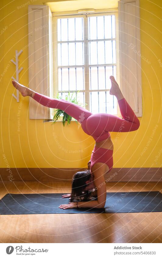 Flexible Frau übt Yoga auf Unterarmen in Pose auf Matte in der Nähe des Fensters üben Dehnung Gleichgewicht einbeiniger Skorpion Asana Unterlage Umkehrung jung