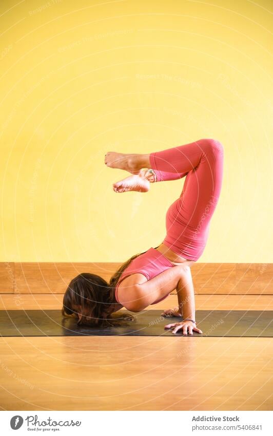 Unerkennbare schlanke Frau auf der Matte macht Skorpion Yoga in Pose im Tageslicht Gleichgewicht beweglich vrischikasana üben Umkehrung Asana Unterlage Wand