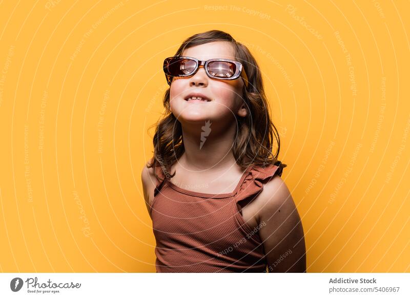 Zufriedenes Kind mit trendiger Sonnenbrille und Badeanzug lächelnd im Studio Mädchen Lächeln Stil Feiertag Sommer positiv Urlaub Porträt Inhalt Model Kindheit