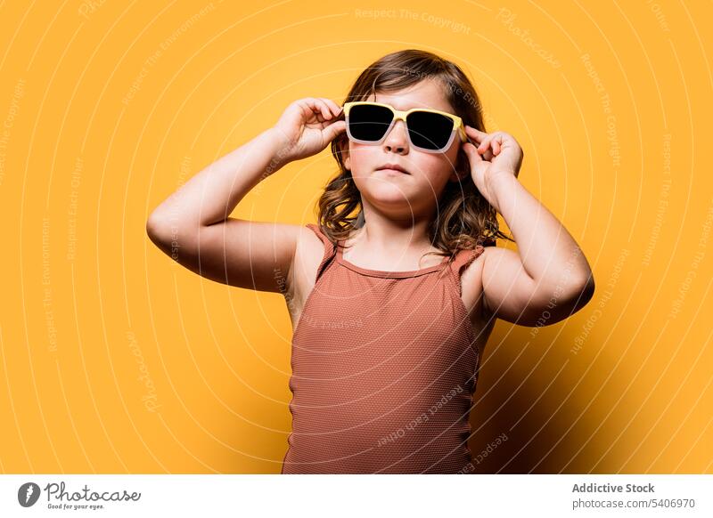 Nettes kleines Mädchen im Badeanzug, das die Sonnenbrille berührt und in die Kamera schaut Stil selbstbewusst Kind Sommer Feiertag cool Porträt ernst Model