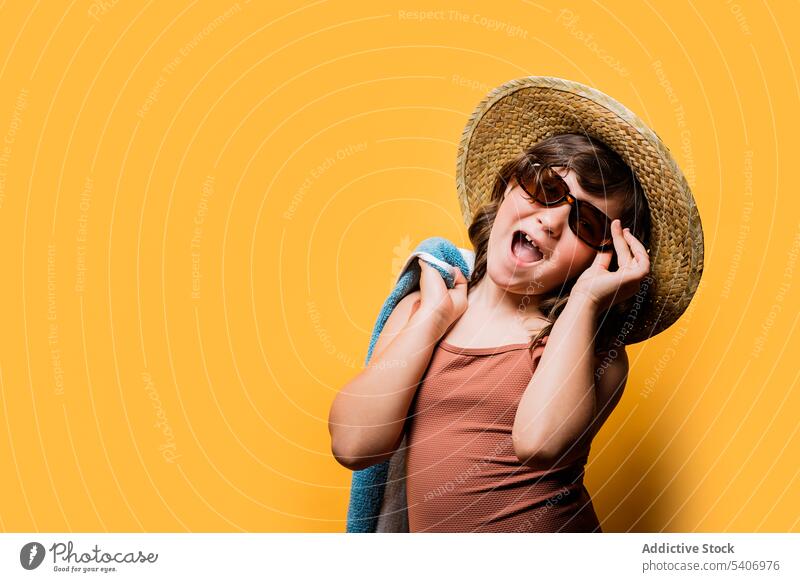 Glückliches, liebenswertes Kind, das seine Sonnenbrille vor einem gelben Hintergrund einstellt Mund geöffnet heiter ausrichten Sommer aufgeregt Mädchen Porträt