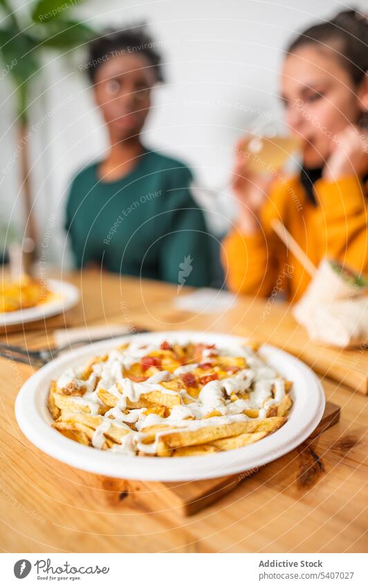 Leckere Käse geladen Pommes frites auf dem Tisch mit unscharfen Menschen im Hintergrund Fries cremig lecker Speise Teller Lebensmittel essen Mittagessen Freund