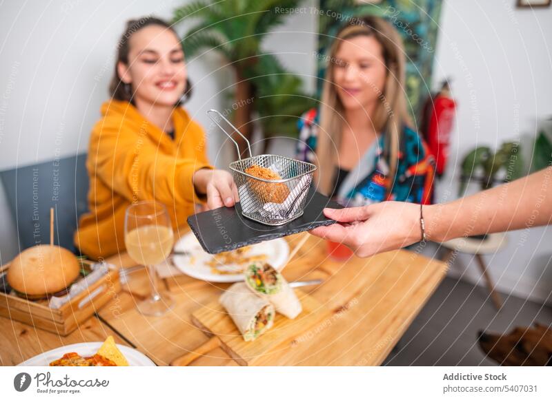 Lächelnde Freunde, die Spaß haben, während sie Snacks und Pommes essen Frauen gebraten Lebensmittel Speise geschmackvoll verschiedene Korb Tisch Freundschaft