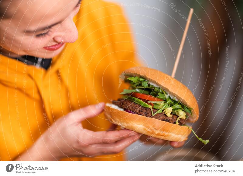 Lächelnde Frau isst Burger im Restaurant essen lecker positiv Lebensmittel geschmackvoll Pause Kantine Gemüse genießen Mittagessen lässig Mahlzeit jung Glück