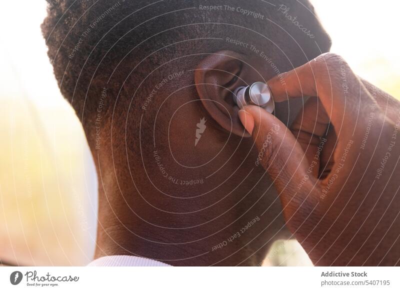 Anonymer schwarzer Mann, der über TWS-Kopfhörer Musik hört zuhören echte drahtlose benutzend Menschliches Gesicht ausrichten Freizeit modern tws Apparatur