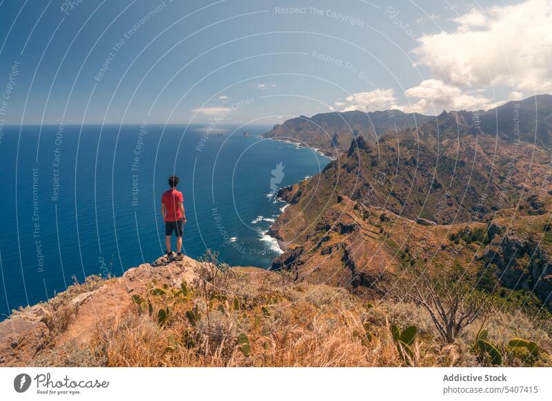 Junger Mann in Freizeitkleidung steht auf einer Klippe und bewundert die Meereslandschaft Berge u. Gebirge Reisender Wanderer Natur MEER Landschaft Abenteuer