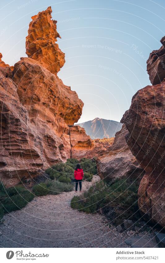 Unbekannte Reisende, die auf einem Kiesweg in der Nähe von Vulkanfelsen steht Frau Tourist bewundern Berge u. Gebirge Natur Landschaft erkunden Stein Felsen