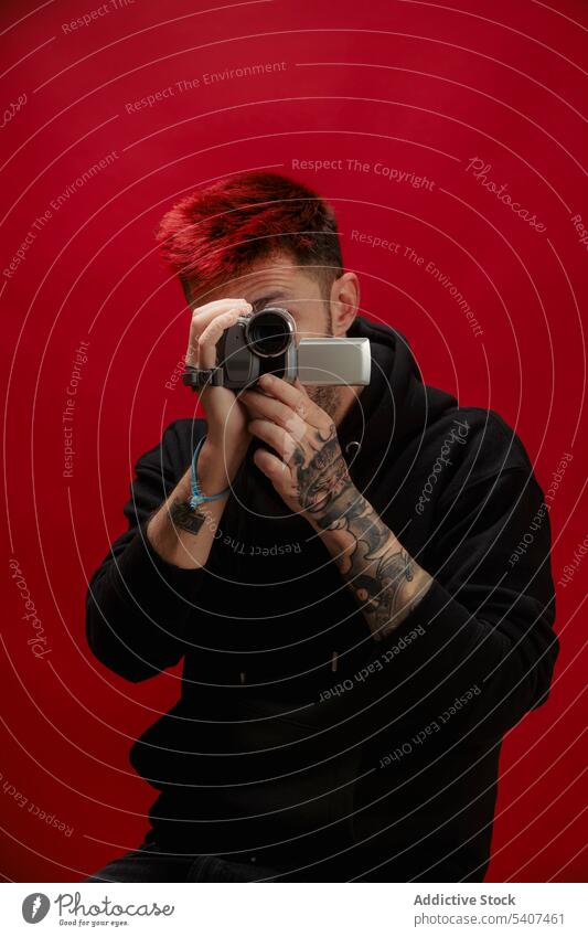 Unbekannter junger Mann, der mit einer Videokamera aufgenommen wird Fotokamera schießen Aufzeichnen benutzend digital Porträt Apparatur Stil modern Amateur