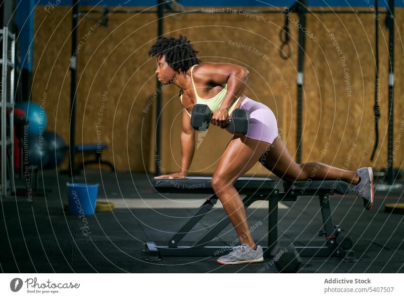 Schwarzer Sportler beim Training auf einer Bank mit Hantel Sportlerin Übung Gewichtheben Kurzhantel schwer Fitness Frau reif Afro-Look Afroamerikaner schwarz